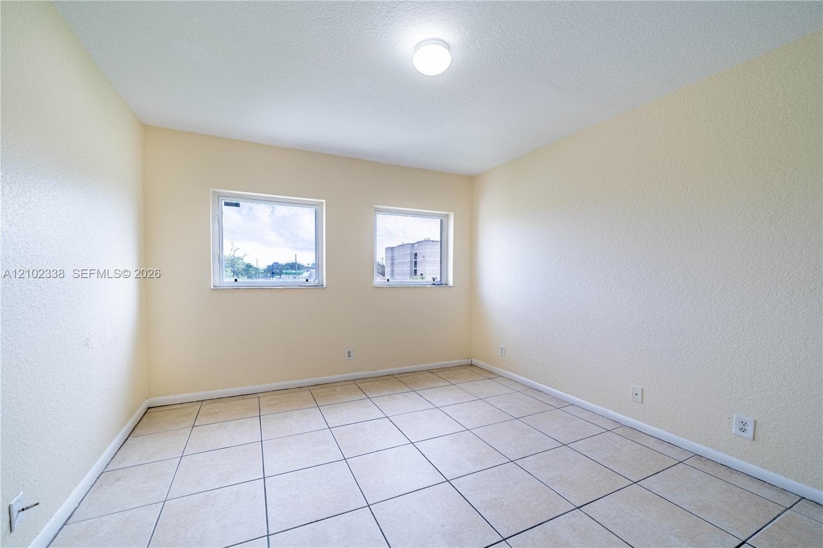 Square tile flooring, dual windows, and a flush mount ceiling light