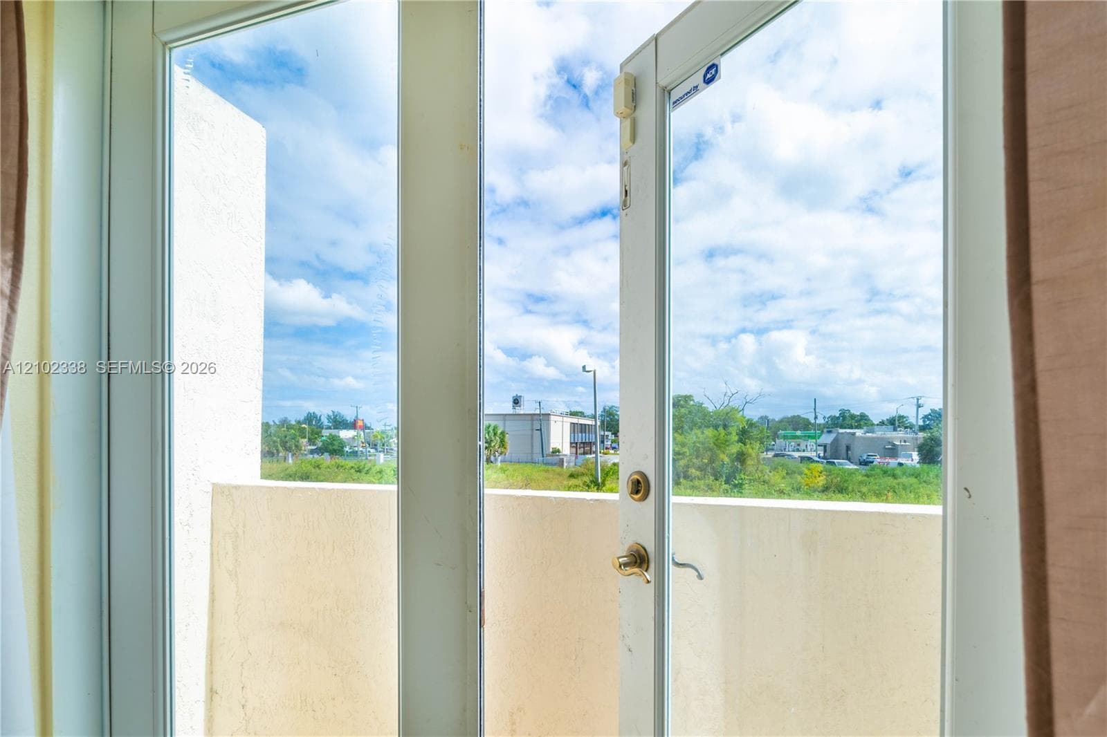 Balcony access with an exterior door featuring a brass handle and a surrounding concrete barrier