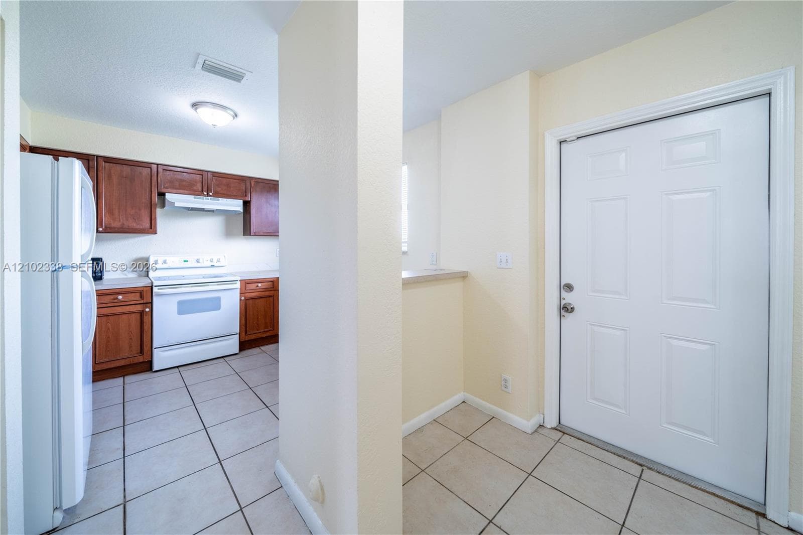 Kitchen featuring wood-finish cabinetry, white appliances, and tiled flooring