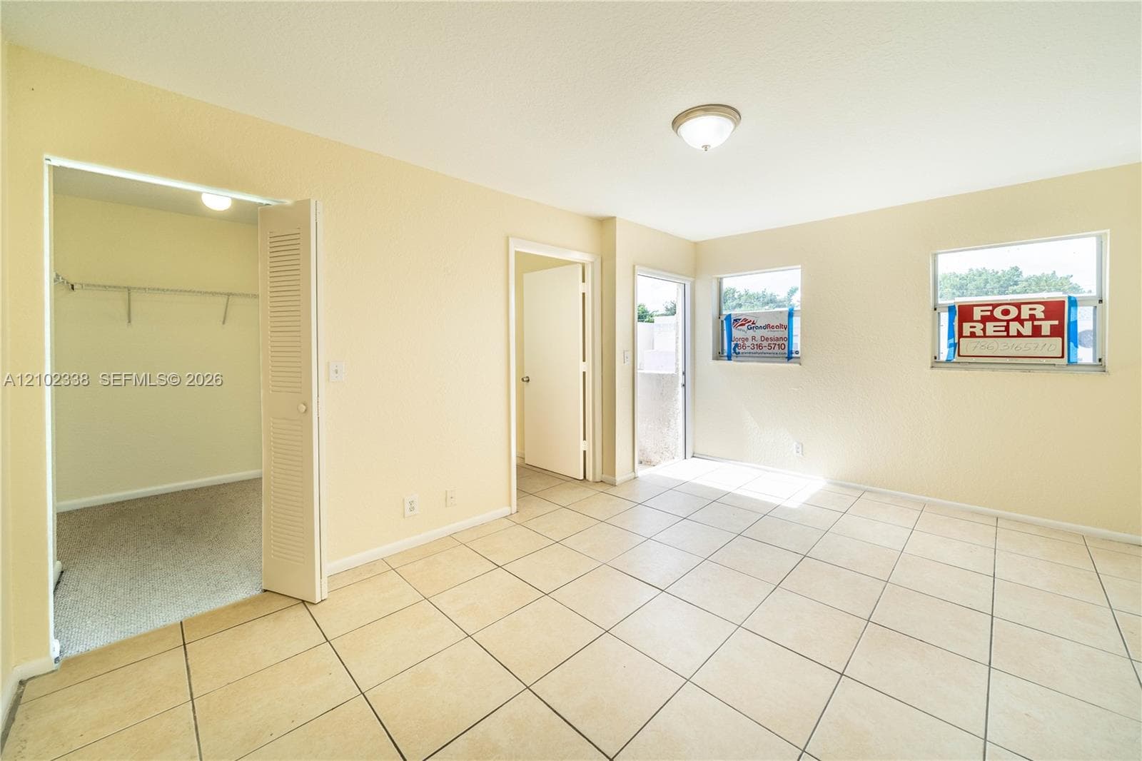 Tiled flooring, double windows, overhead lighting fixture, and a closet with bi-fold louvered doors