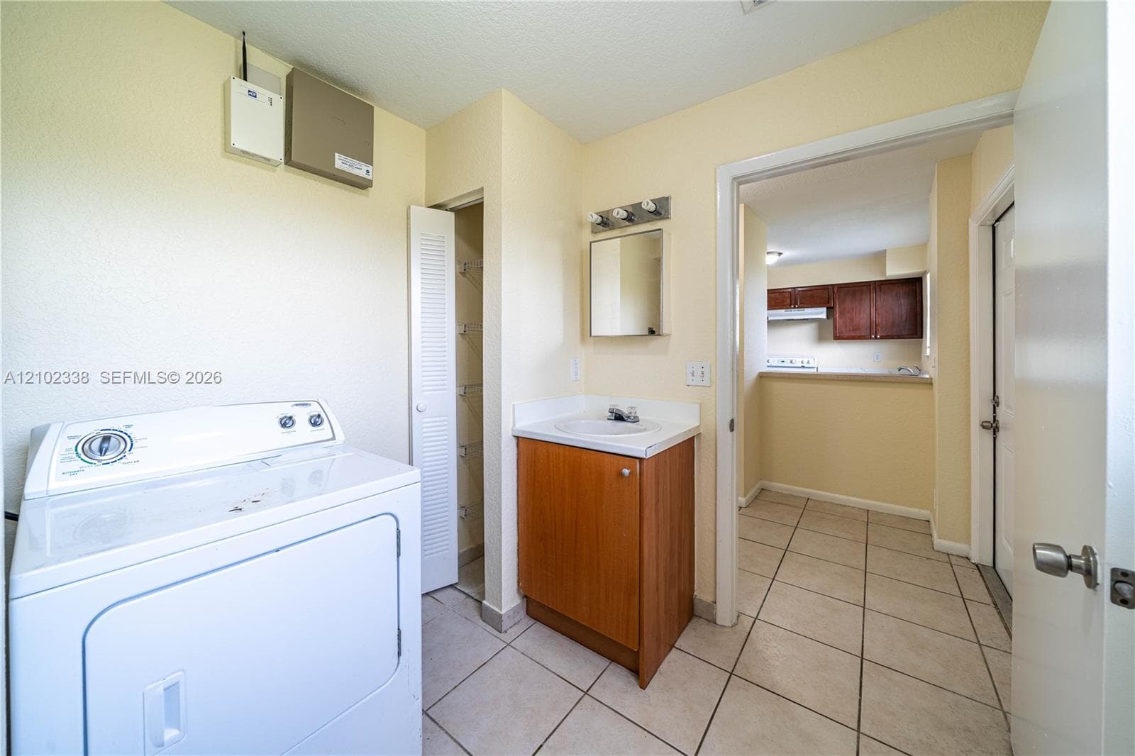 Tiled flooring throughout, vanity with wood-finish cabinetry, and a built-in closet with louvered doors