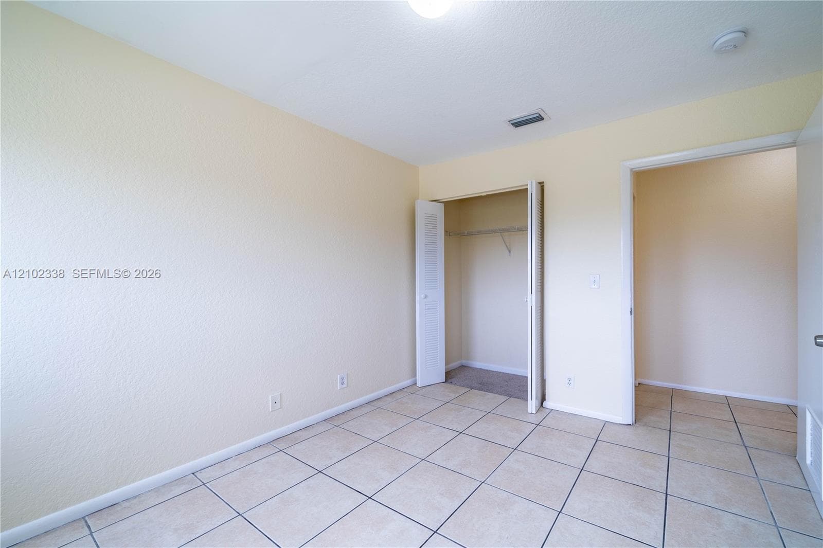 Tile flooring, neutral wall tones, bi-fold closet doors, built-in shelving, and recessed ceiling lighting