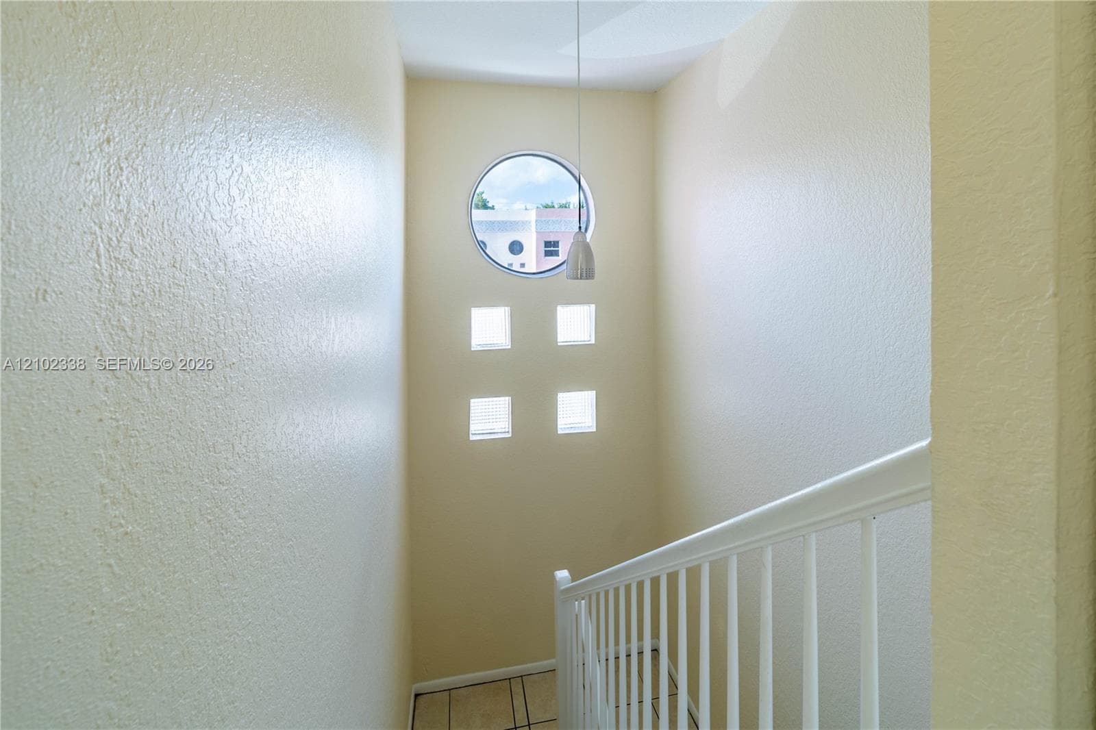 Two-story foyer with a circular window, four square accent windows, and a hanging pendant light fixture