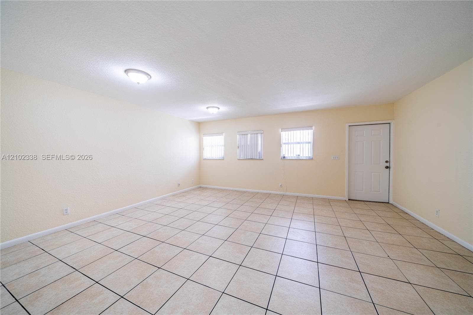 Tile flooring, multiple windows with blinds, recessed lighting, and a paneled entry door