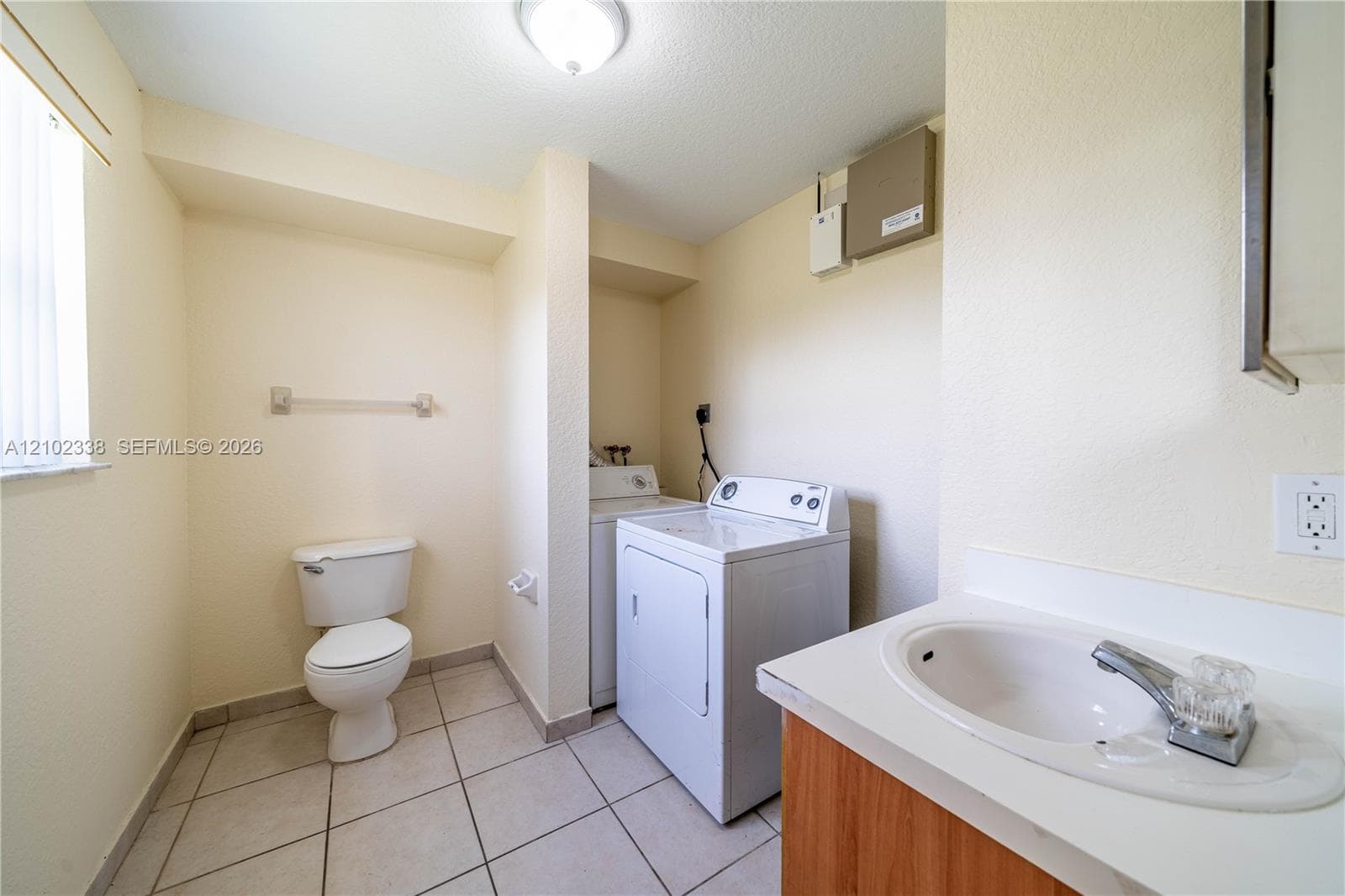 Utility room with tile flooring, a single vanity with a laminate countertop, and a toilet