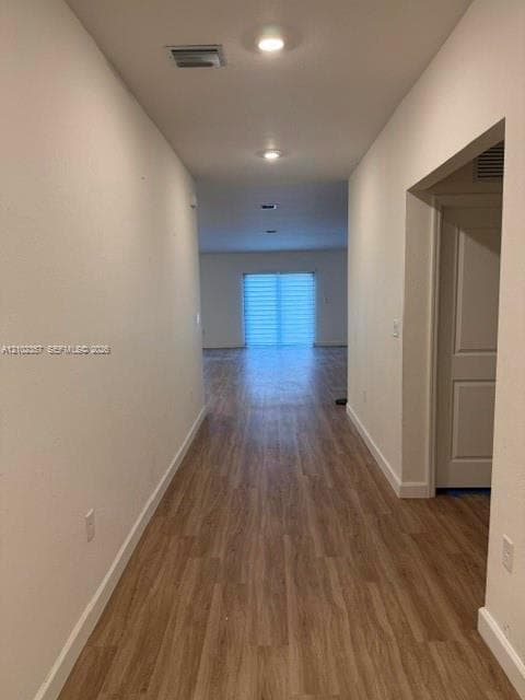 Interior hallway featuring wood-finish flooring, recessed lighting, and sliding glass doors with horizontal blinds