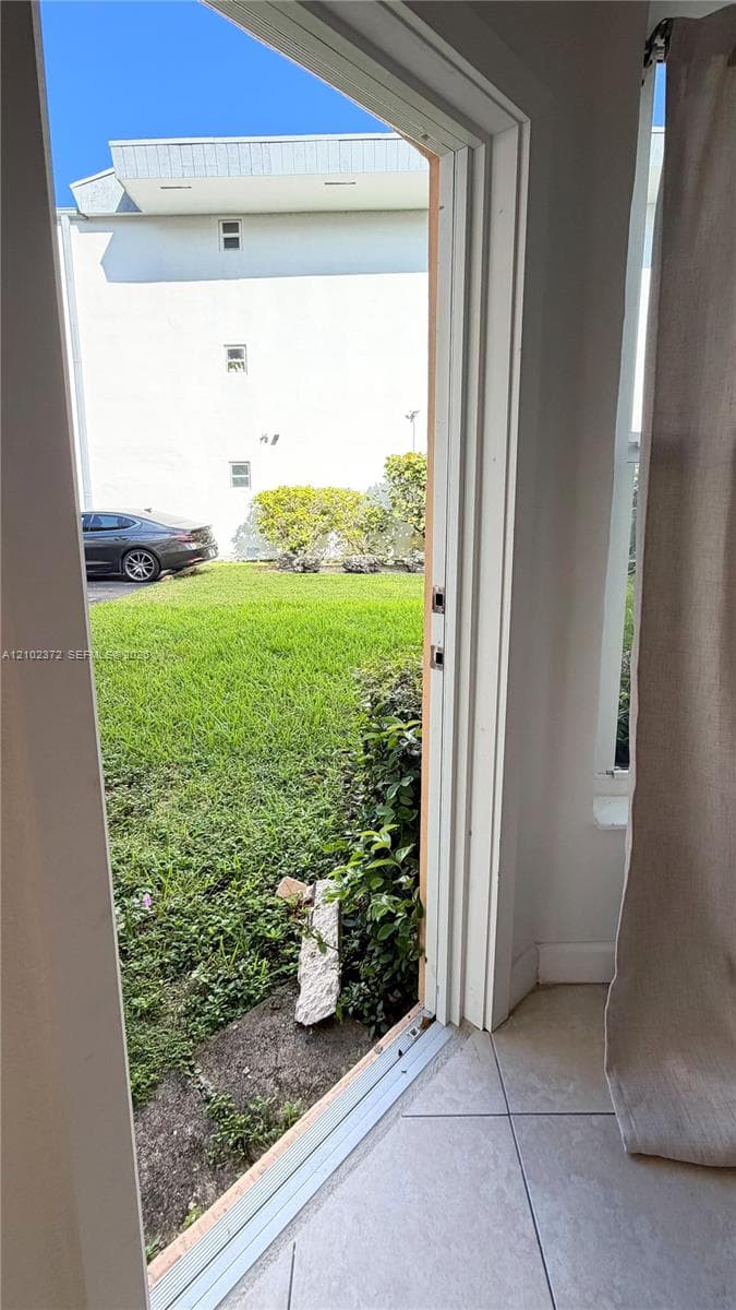 Exterior door opening to a lawn with tile flooring and interior trim