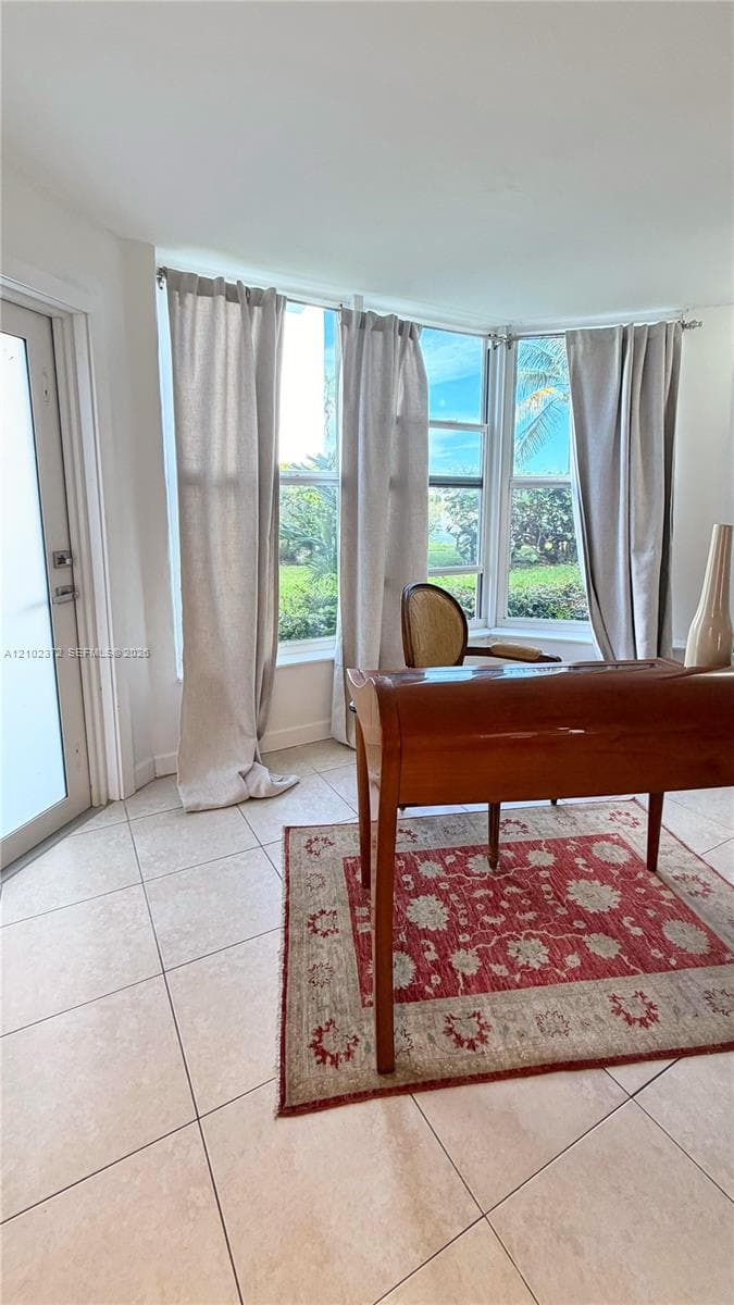 Bay window featuring multi-pane glass panels, light-toned tiled flooring, and a glass-paneled exterior door
