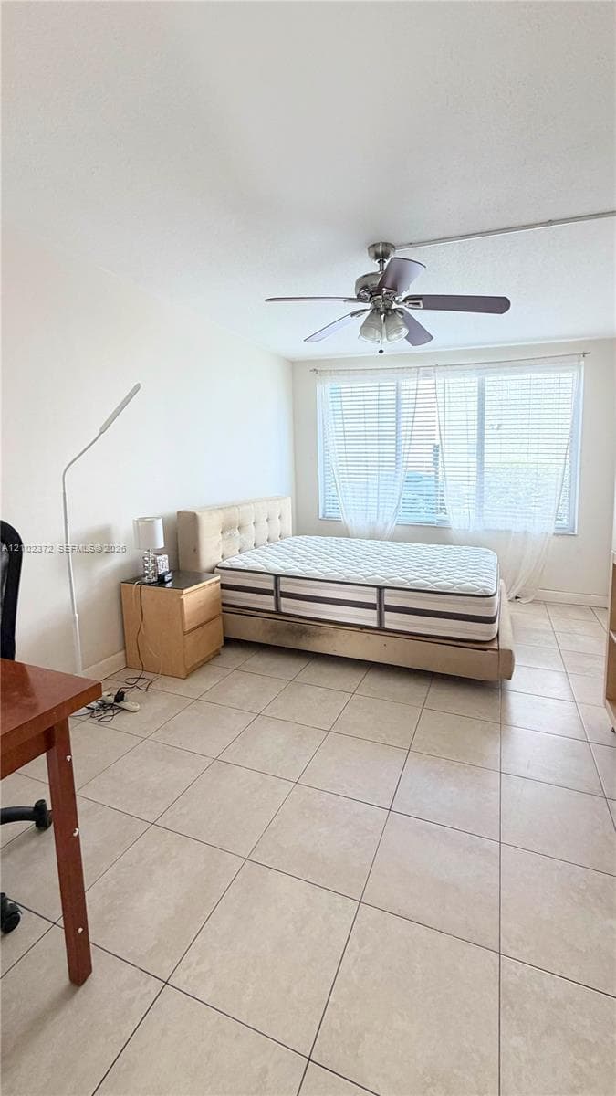Neutral-toned tile flooring, large multi-pane window, and overhead ceiling fan with integrated lighting