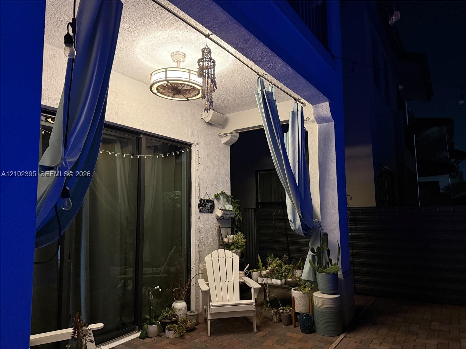 Covered patio featuring sliding glass doors, a drum-style ceiling fan with integrated lighting, and brick paver flooring