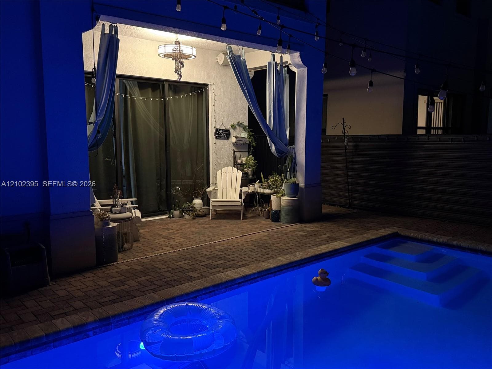 Covered patio featuring paver flooring, a recessed ceiling fixture, and sliding glass doors, extending to a pool with integrated steps