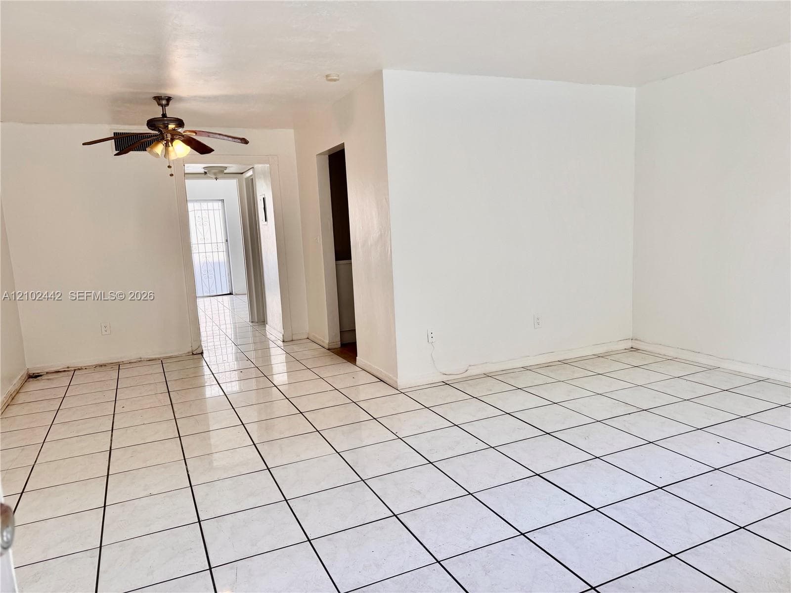 White tile flooring with dark grout, white painted walls, and a ceiling fan with integrated lighting