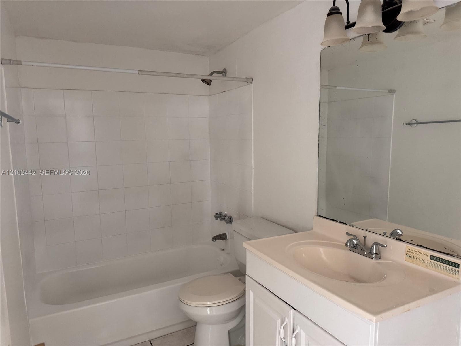 Bathroom featuring a white tiled shower, integrated bathtub, and a vanity with a drop-in sink