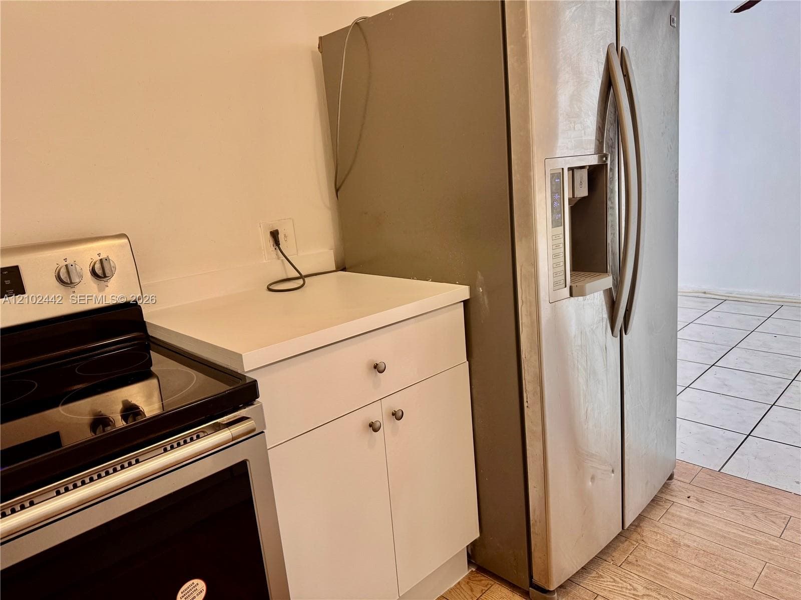 White cabinetry with brushed nickel hardware, a white countertop, and a stainless steel electric range