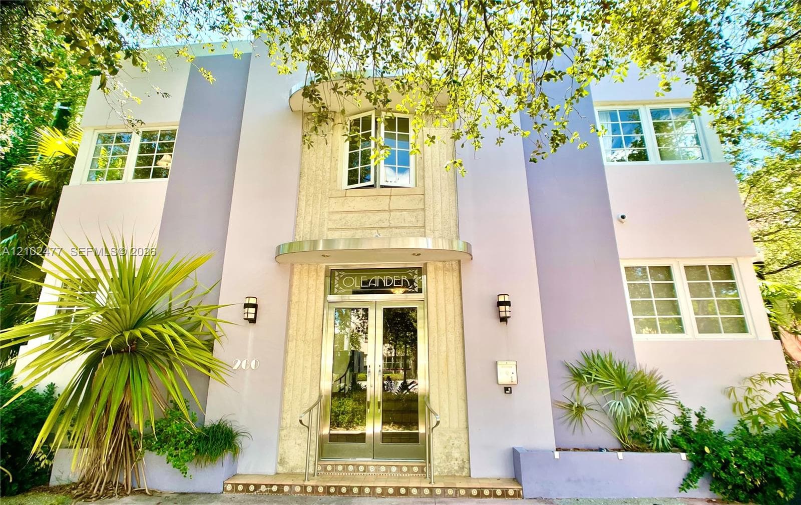 Art Deco architectural facade featuring vertical masonry detailing, symmetrical multi-pane windows, arched entry hood, and glass-paneled double doors