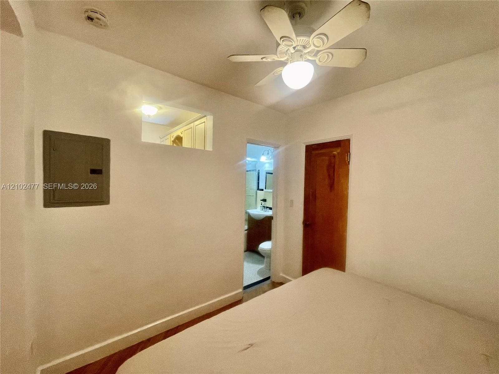 Wood-finish flooring, ceiling fan with integrated light, interior transom window, and solid-core wood door