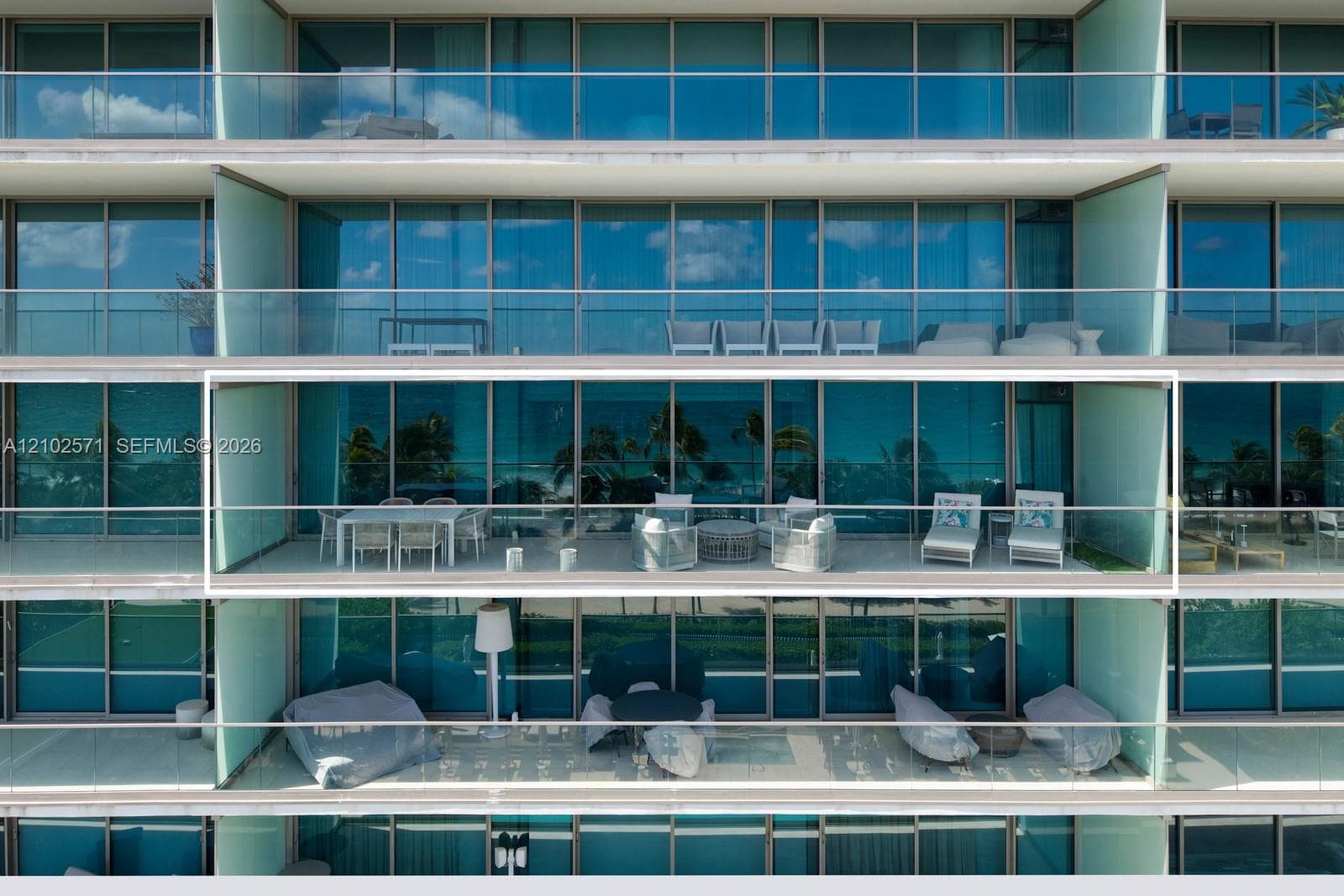 Expansive balcony featuring floor-to-ceiling glass doors, metal railings, and concrete flooring