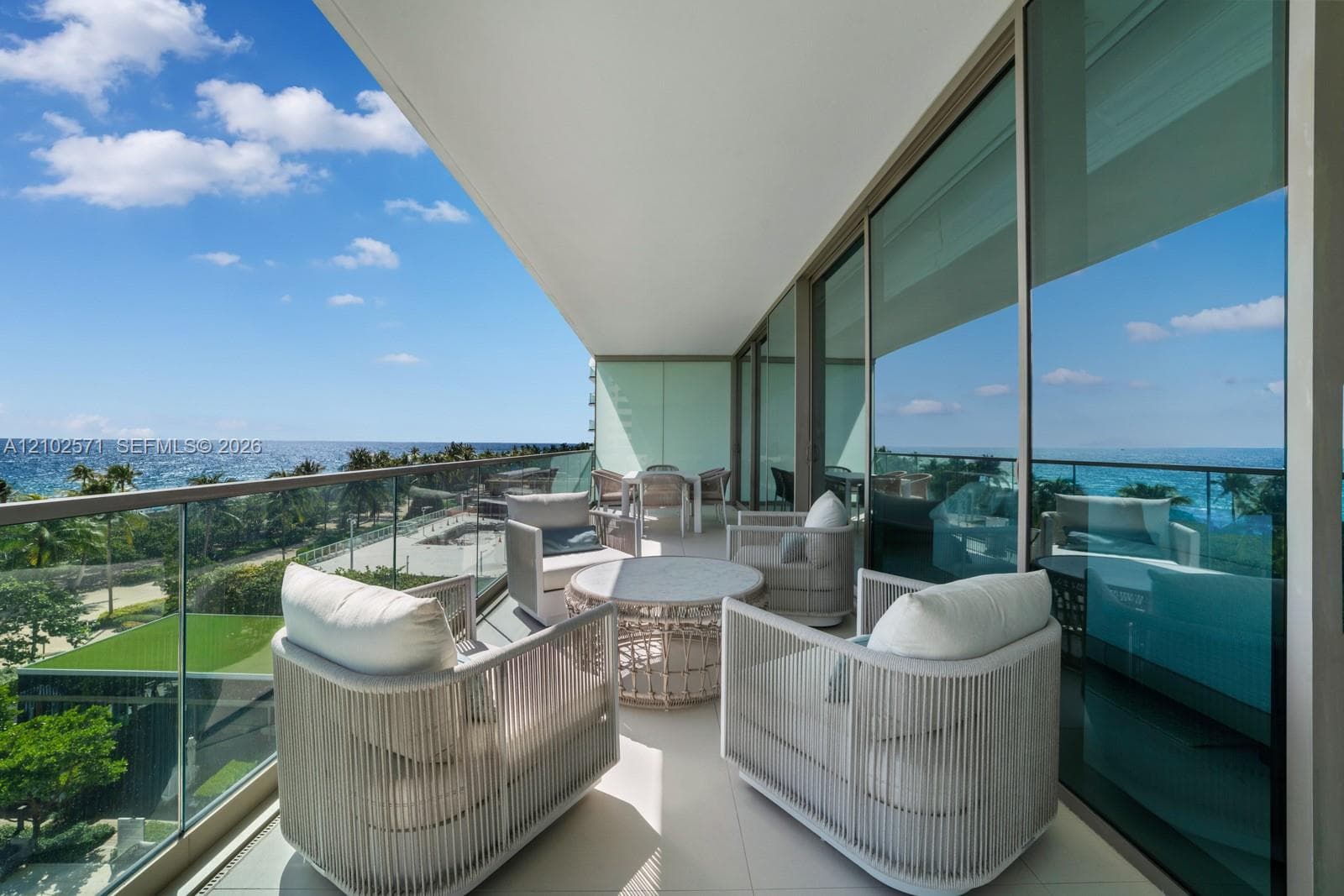 Covered balcony featuring oversized tile flooring, a glass panel railing, and full-height sliding glass doors
