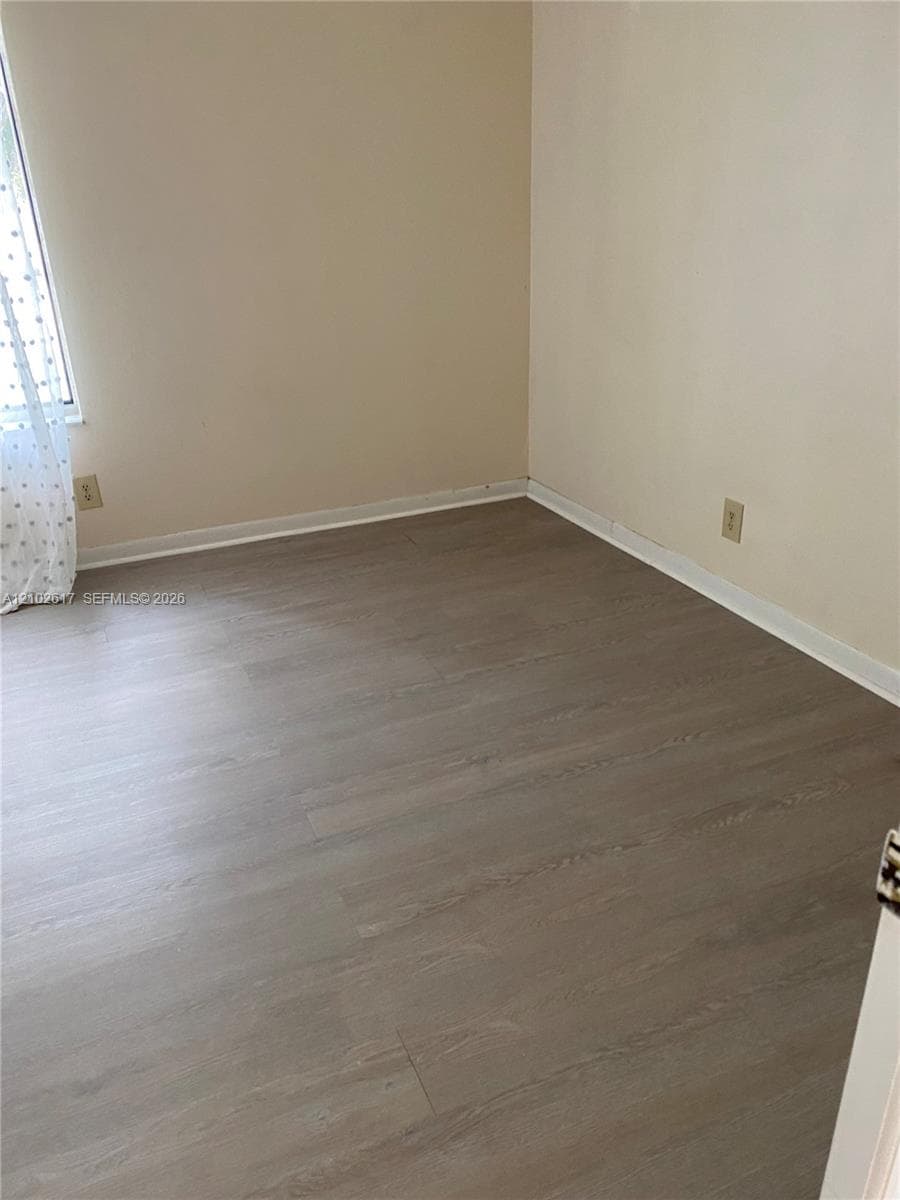 Neutral wall paint, wood-finish flooring, and natural lighting from a single window