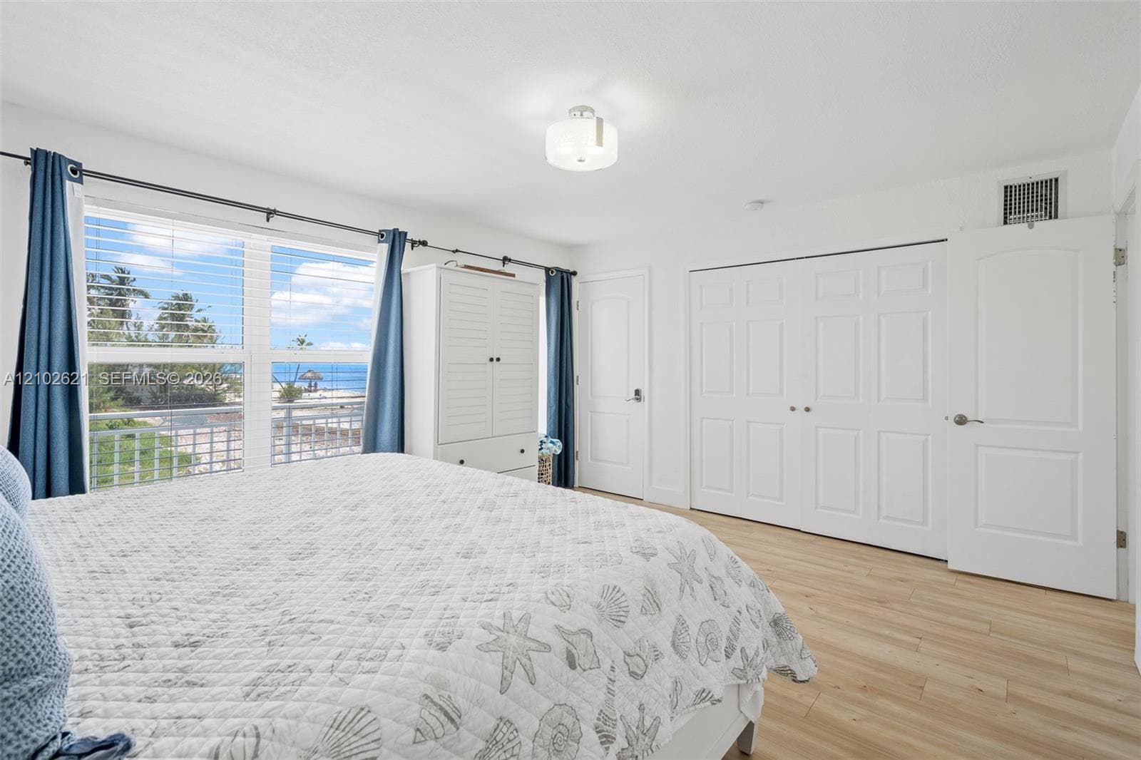 Expansive window with ocean scenery, wood-finish flooring, white paneled doors, and a ceiling-mounted light fixture