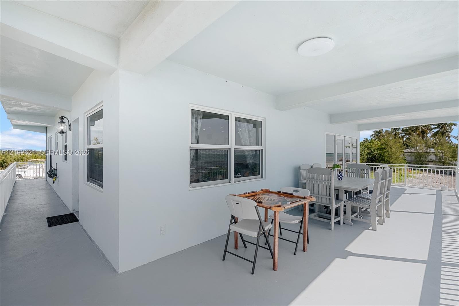Expansive covered outdoor living area featuring multiple windows and a white railing
