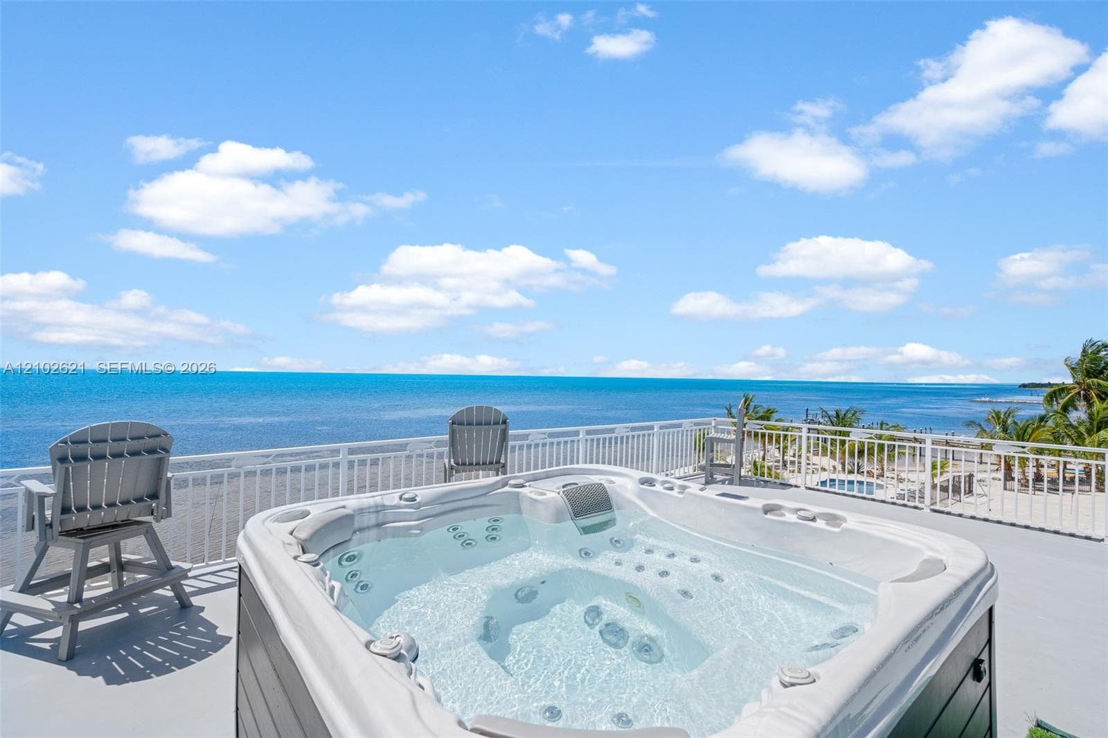 Rooftop deck featuring a hot tub, white railing, and water scenery