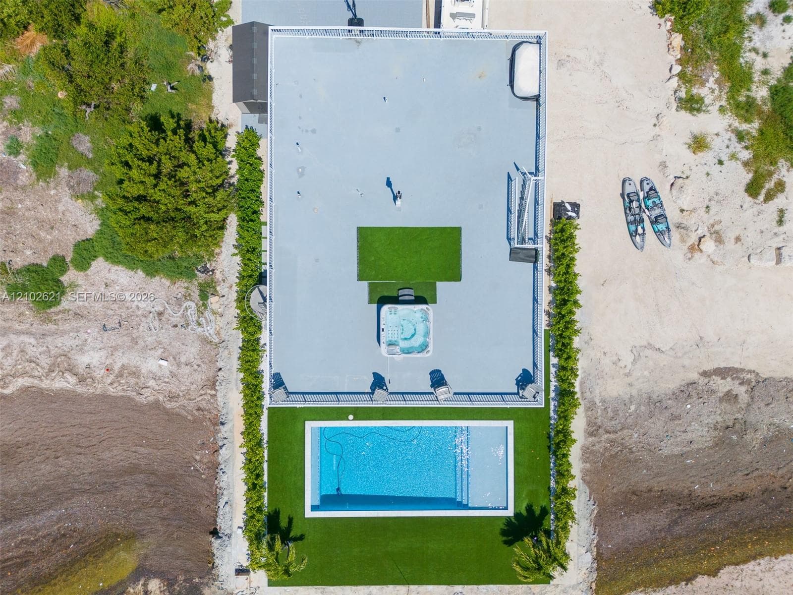 Rooftop deck featuring a spa, artificial turf areas, an in-ground swimming pool, and established perimeter plantings