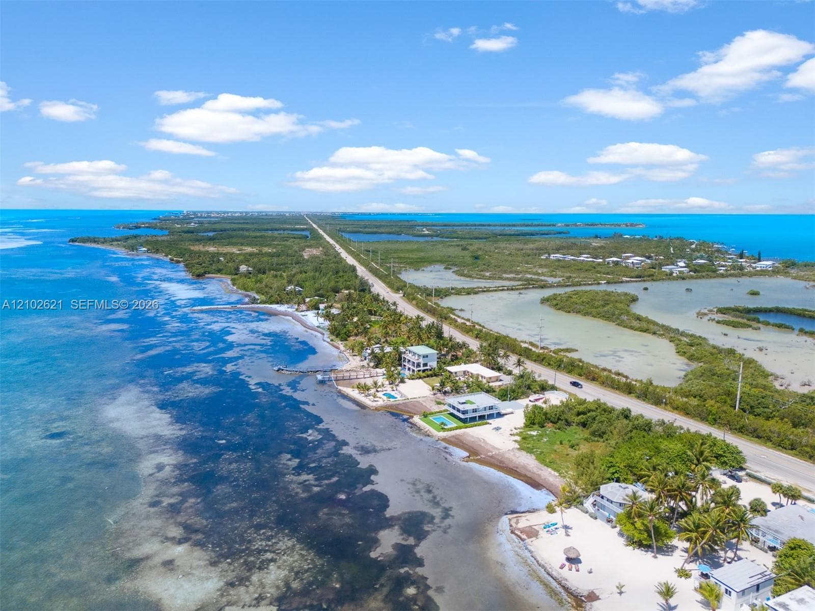 Coastal property with direct water frontage, a private pier, and a sandy beach area