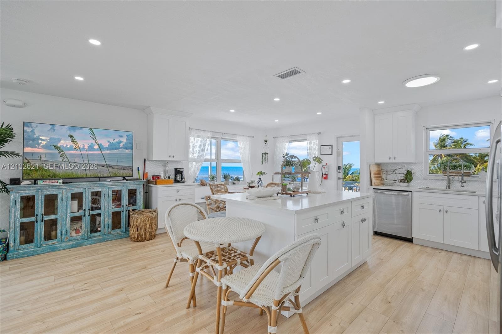 Kitchen featuring white cabinetry, a kitchen island, stainless steel appliances, wood-finish flooring, and recessed lighting
