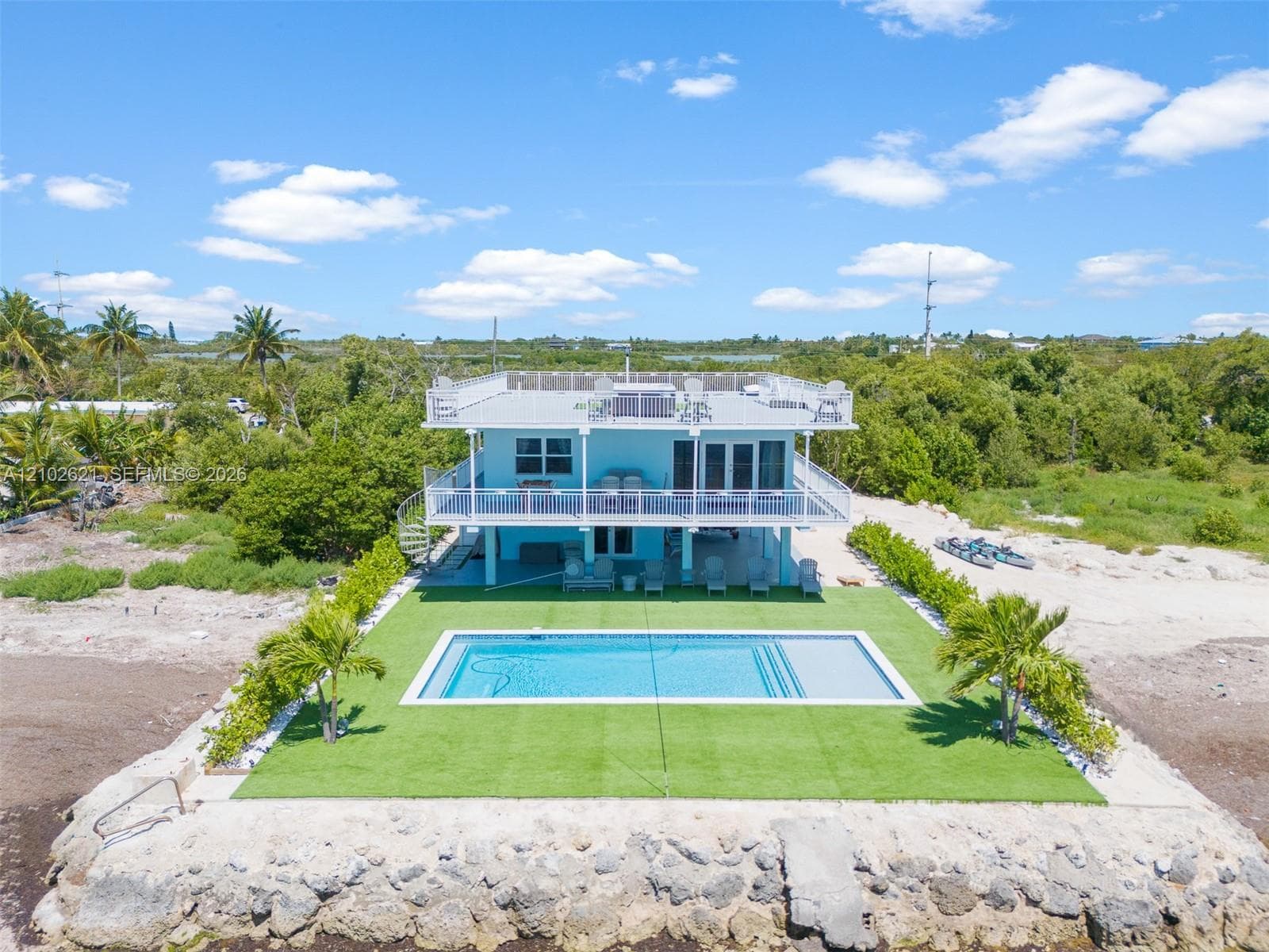 Elevated two-story residence featuring a rooftop deck, an inground swimming pool, a ground-level patio, a second-story balcony, and a spiral staircase