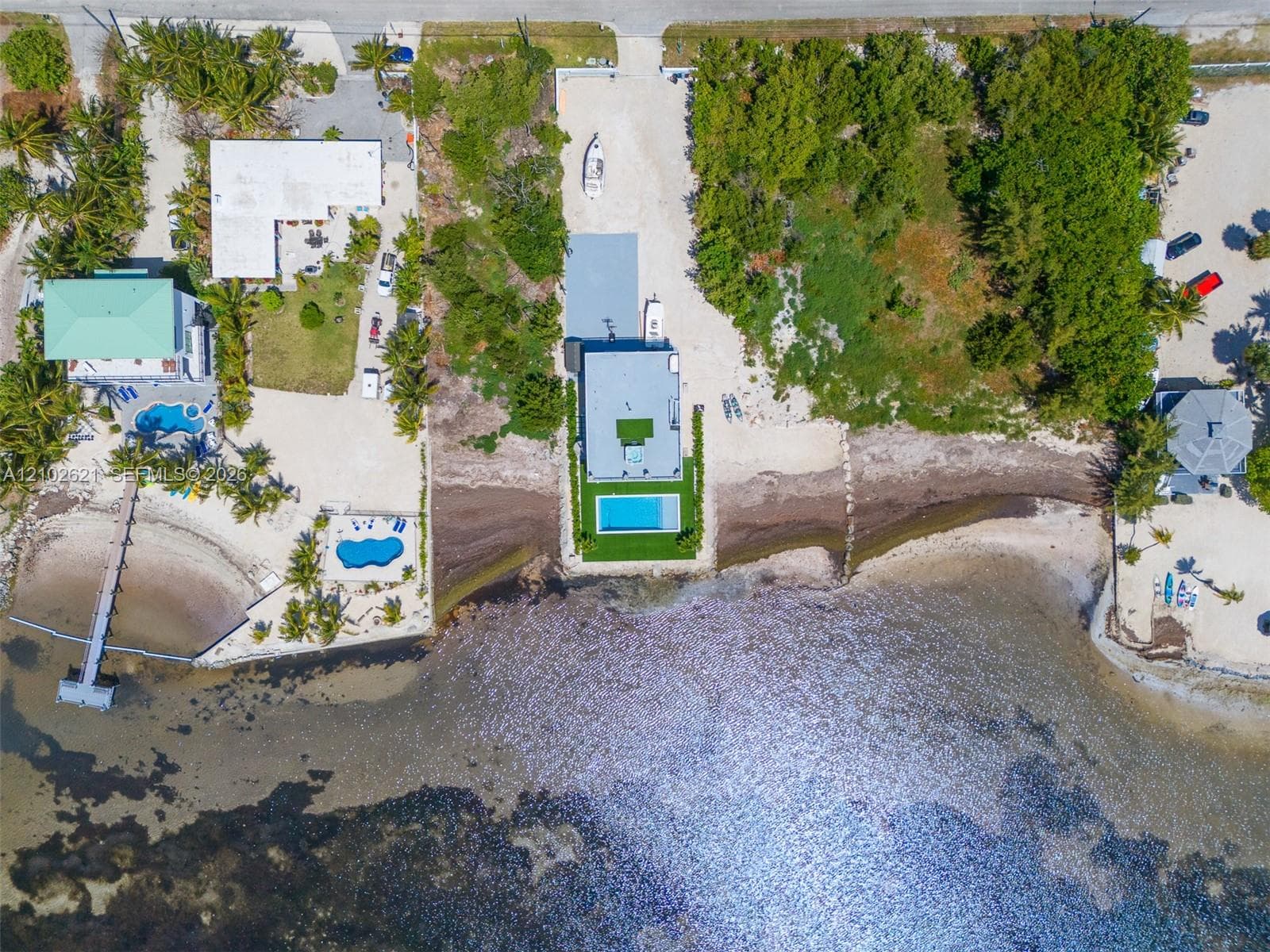 Waterfront property featuring a private dock, two distinct swimming pools, and extensive shoreline access