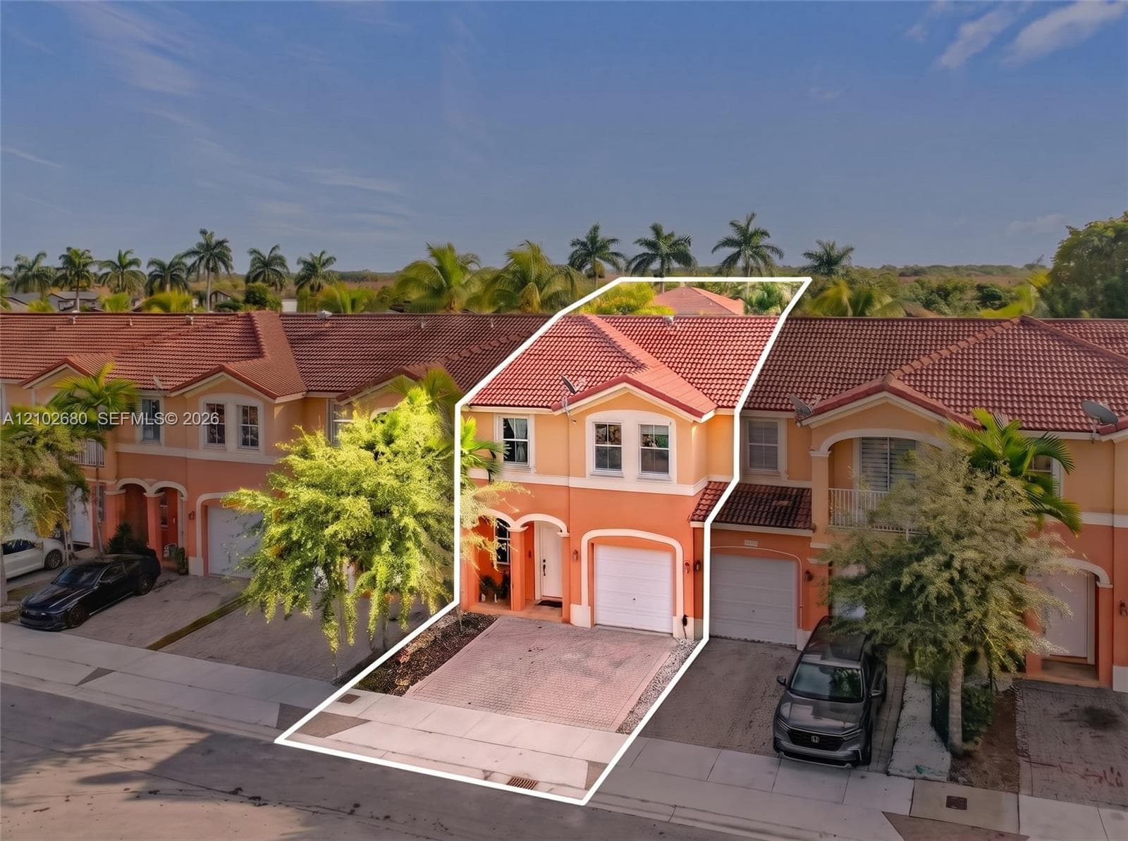 Two-story exterior featuring a tile roof, stucco facade, paved driveway, and single-car garage