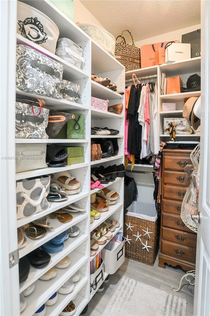 Custom reach-in closet featuring extensive white built-in shelving, adjustable cubbies, and a horizontal hanging rod