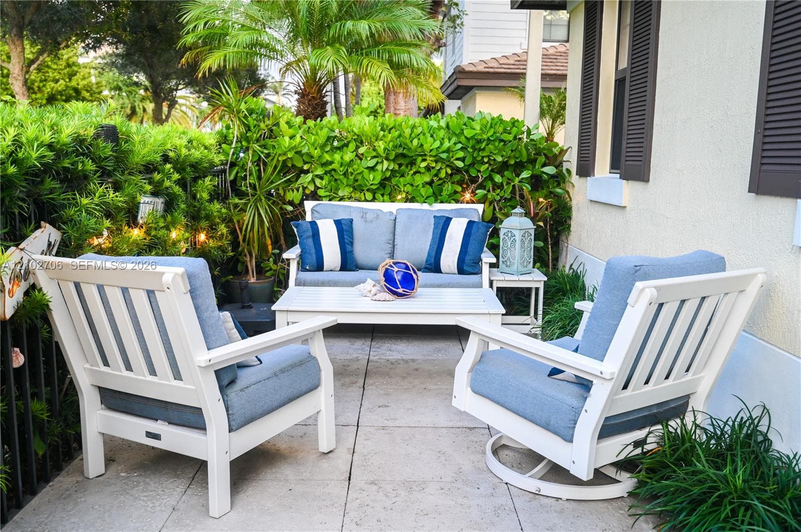 Patio area featuring concrete pavers, stucco exterior wall, and integrated privacy hedge