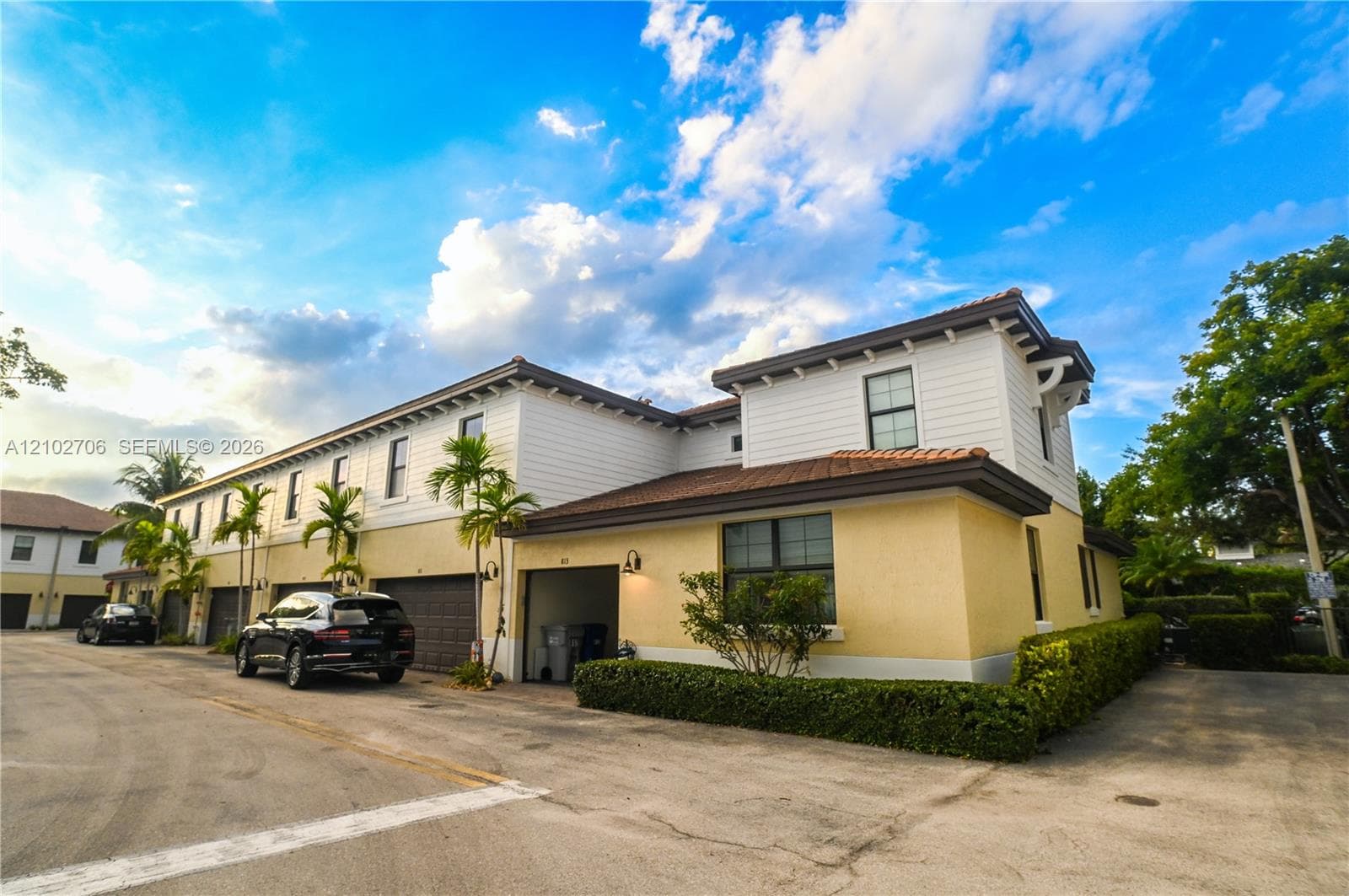 Two-story exterior featuring a mix of horizontal lap siding and textured stucco finish, a multi-section tile roof, and multiple attached garage bays