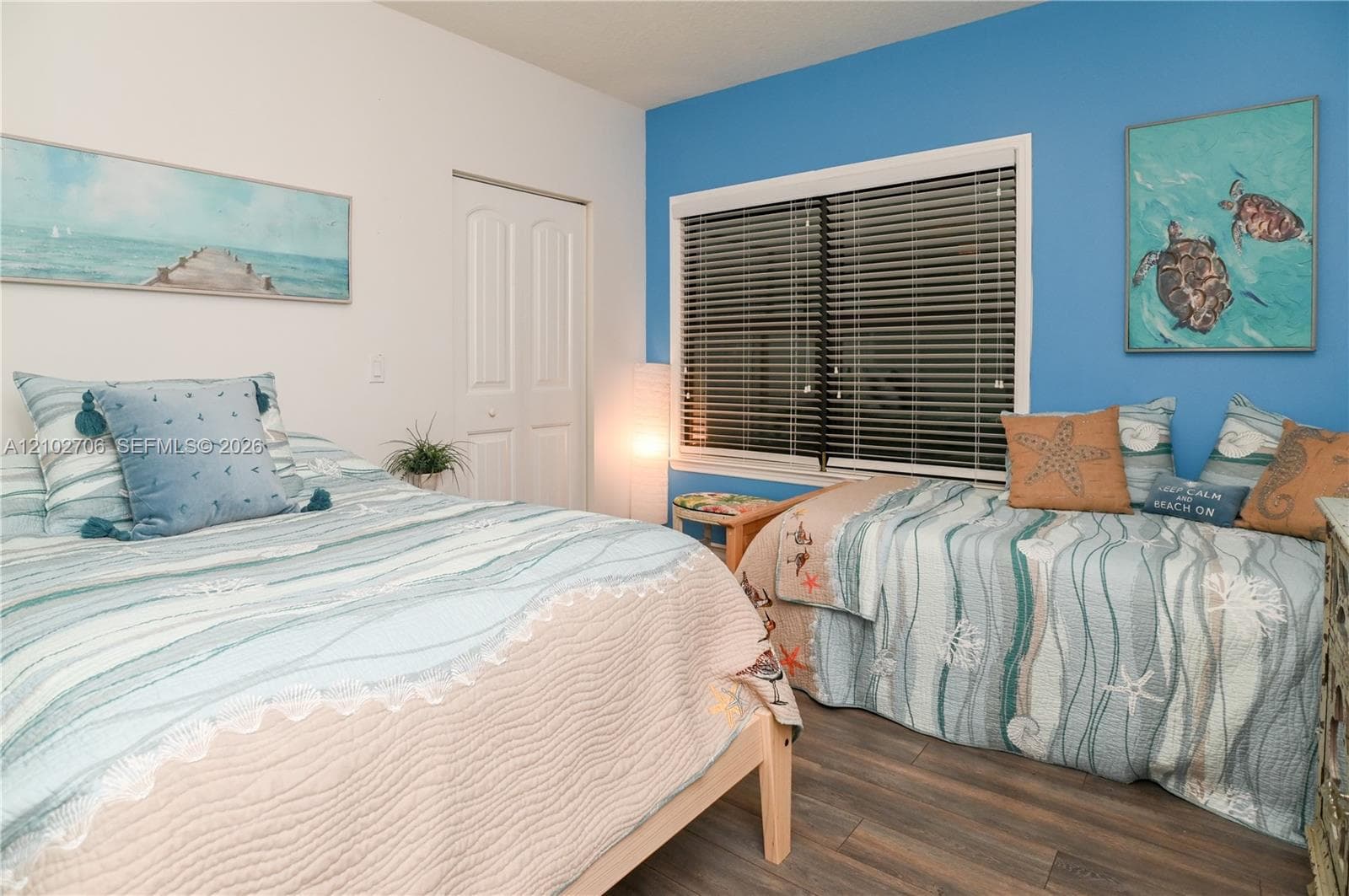 Room with wood-finish flooring, accent wall, and multi-panel interior door featuring horizontal blinds