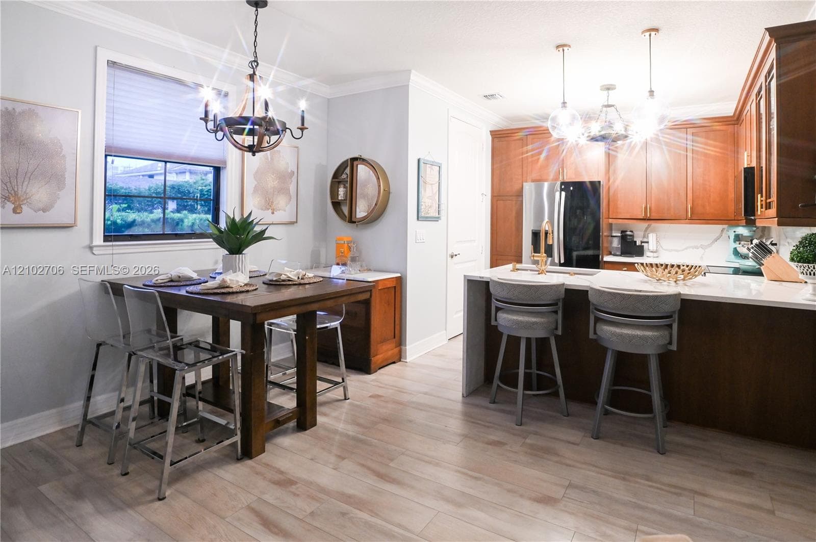 Kitchen featuring wood cabinetry, stone countertops, central island, wood-finish flooring, and crown molding