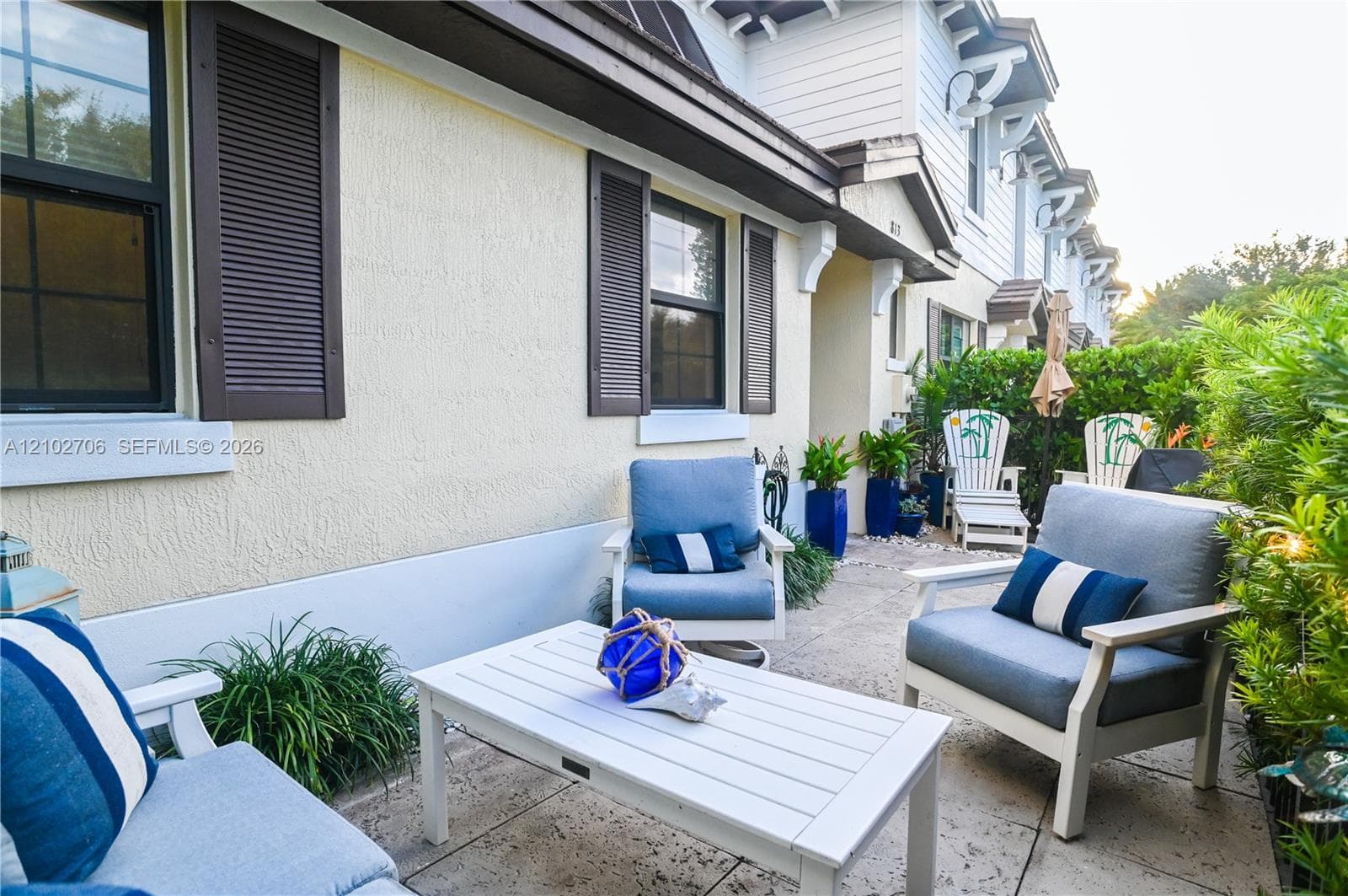Stone-paver patio featuring exterior stucco walls, decorative dark shutters, and wall-mounted light fixtures