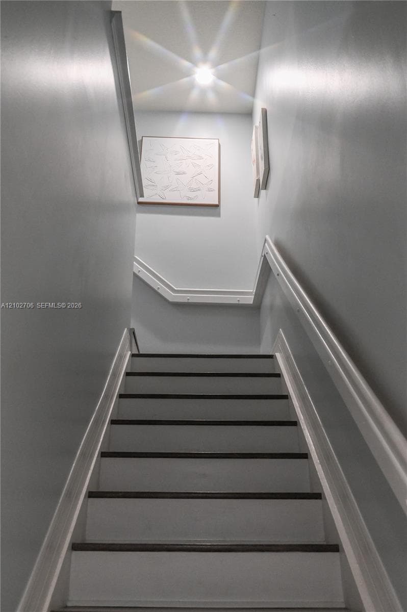 Staircase featuring dark wood-finish treads, white painted risers, and decorative millwork handrails