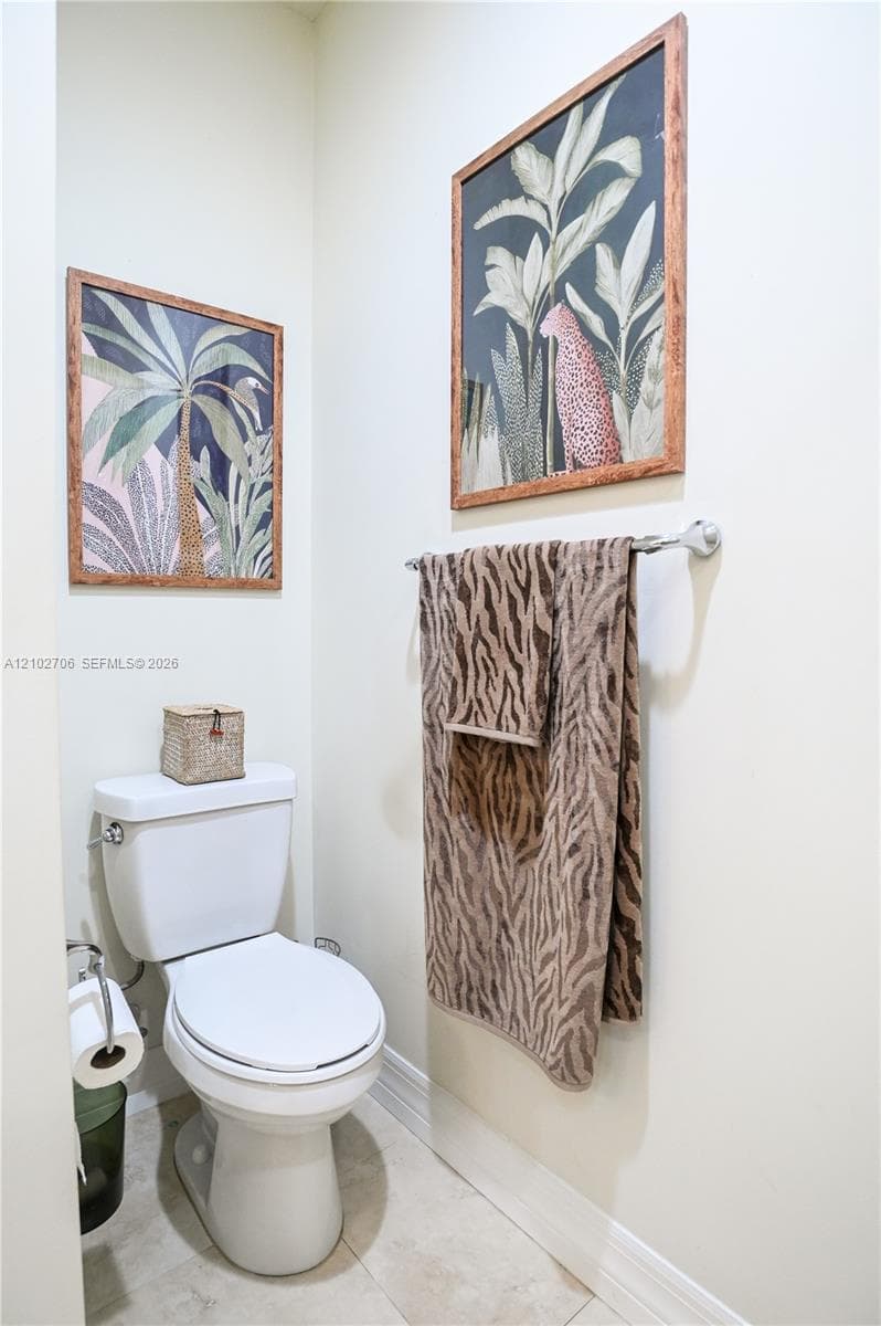 Ceramic toilet, polished chrome towel bar, and neutral floor tile