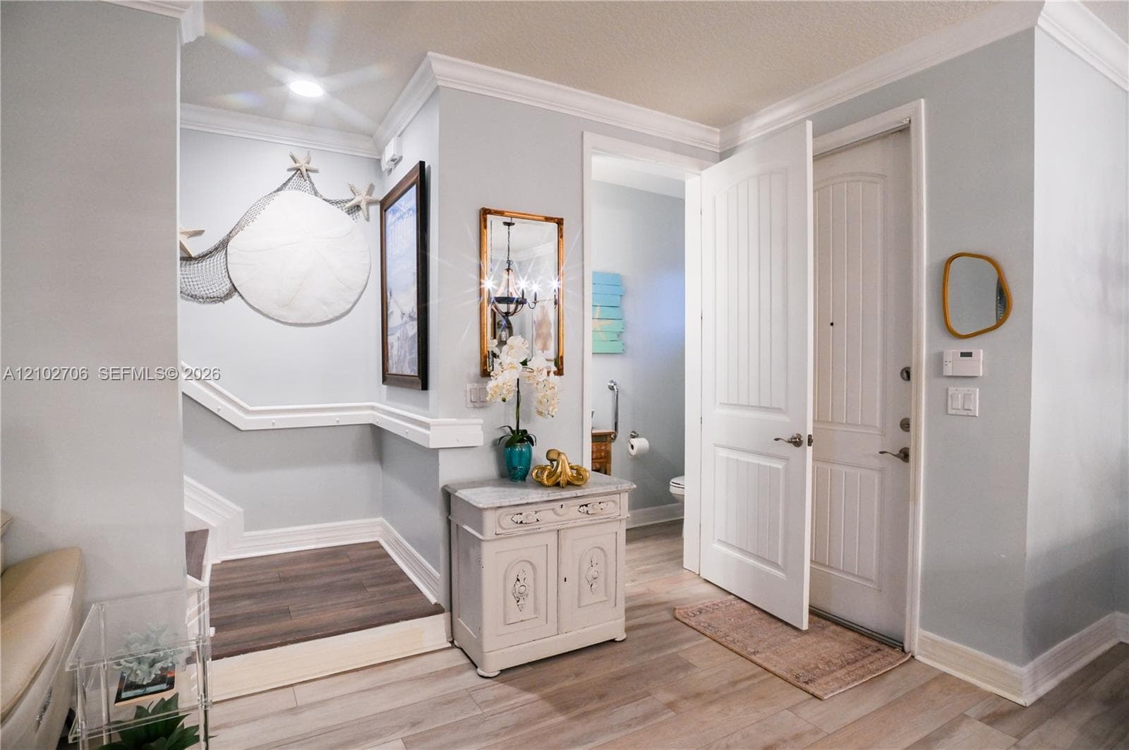 Entryway featuring wood-finish flooring, decorative crown molding, and a multi-panel door with brushed metal hardware