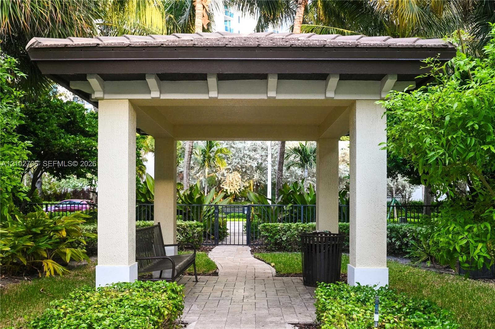 Covered pavilion featuring a tiled roof, stucco-finished columns, and a stone-paver walkway