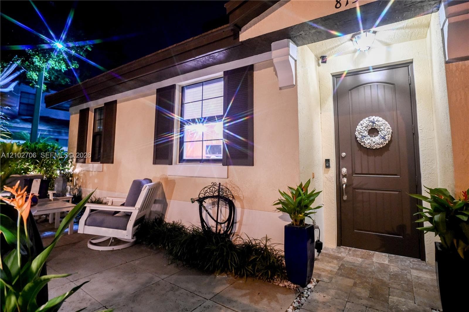 Stucco exterior featuring decorative shutters, stone-paver flooring, a solid-panel entry door, and ornamental corbel accents