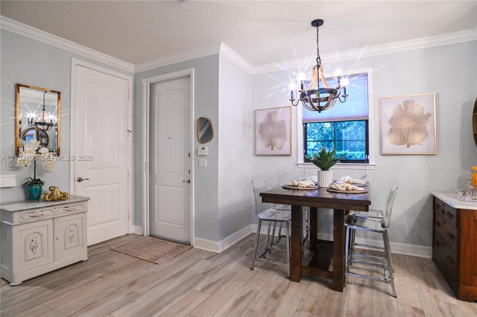 Dining area featuring wood-finish flooring, crown molding, a multi-light metal chandelier, and a multi-pane window