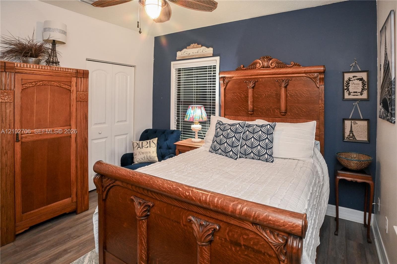 Wood-finish flooring, accent wall, ceiling fan with integrated lighting, and white paneled closet doors