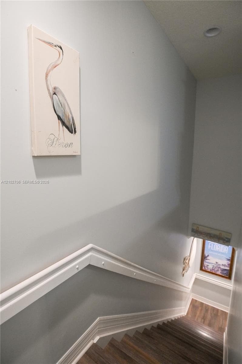 Staircase featuring wood-finish flooring, two-tone wall paint, white chair rail molding, and recessed ceiling lighting