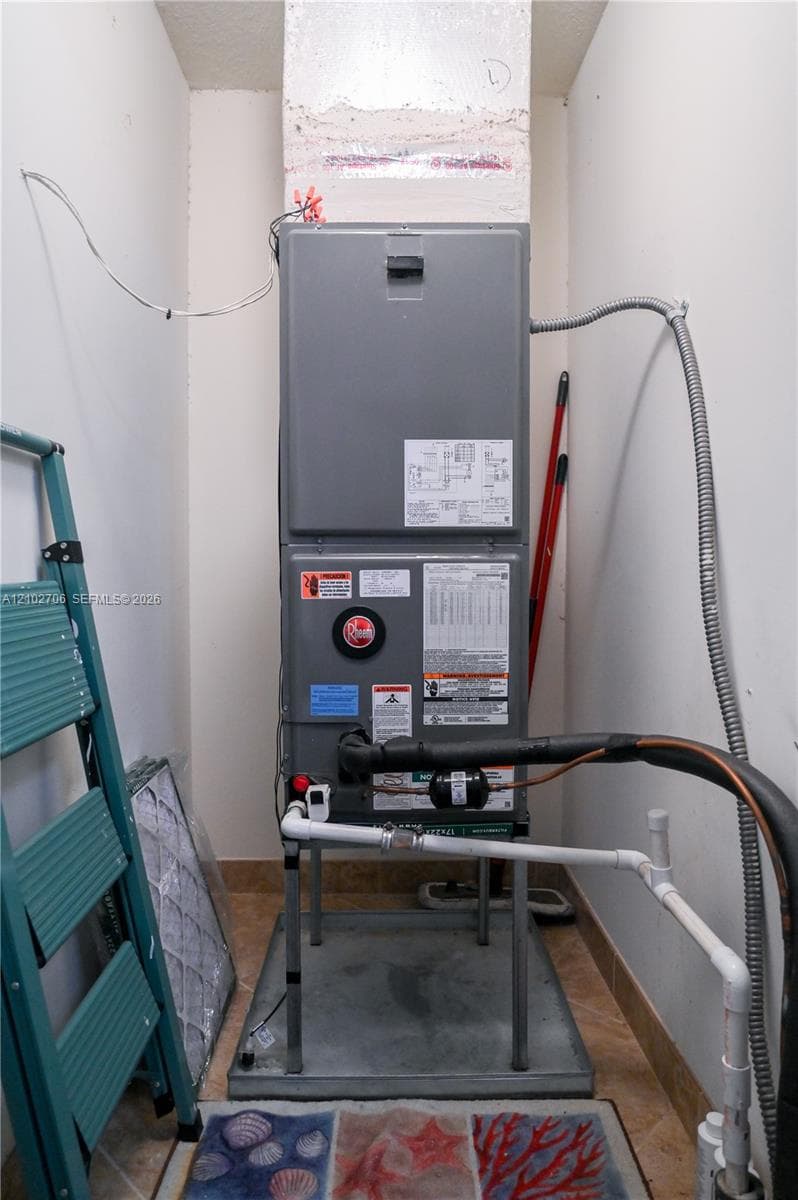 Upright HVAC unit featuring a metal enclosure, protective drain pan, and dedicated plumbing components