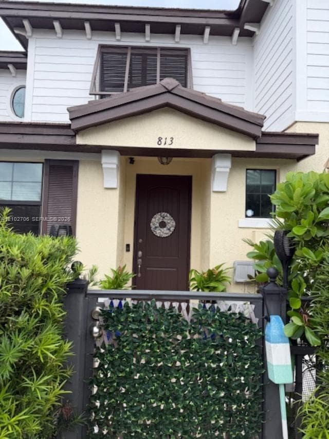 Exterior entrance featuring a covered porch, wood-paneled door, multi-material facade, and metal gated entryway