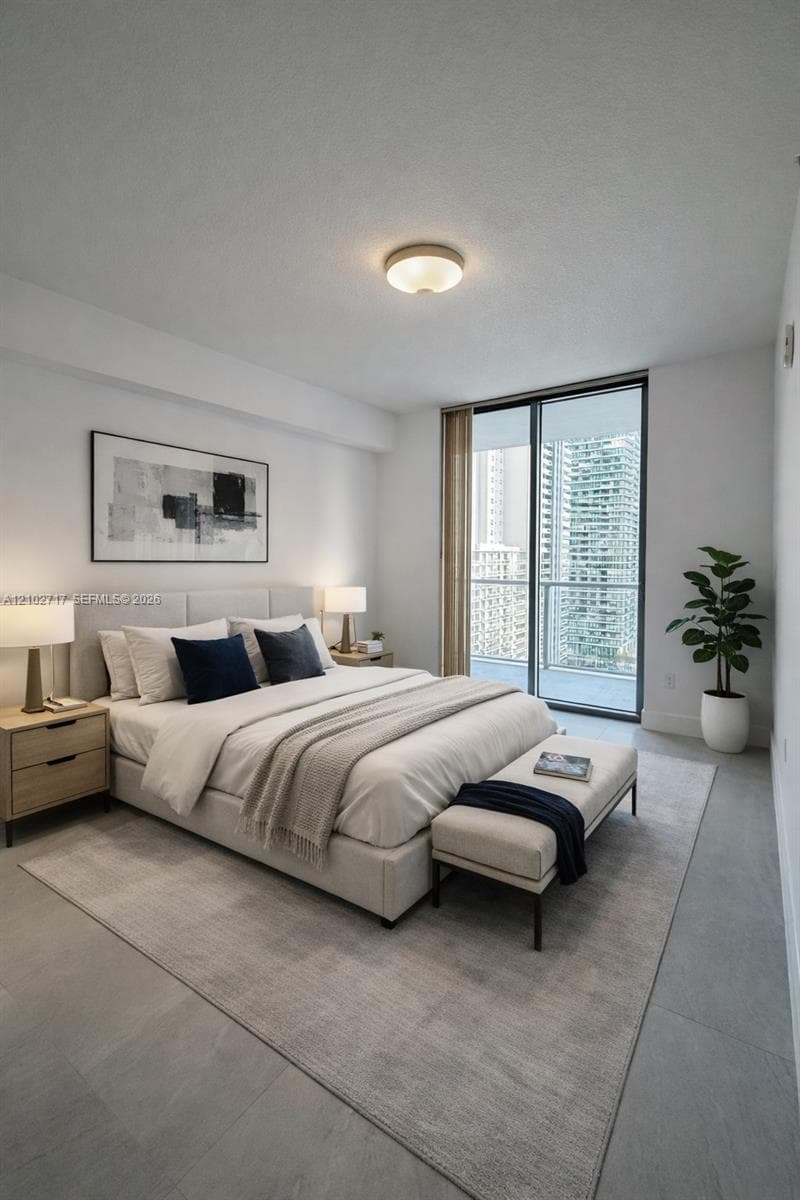 Neutral-toned interior space featuring expansive floor-to-ceiling glass sliding doors, a metal-railing balcony, smooth-finish flooring, and a flush-mount overhead light fixture