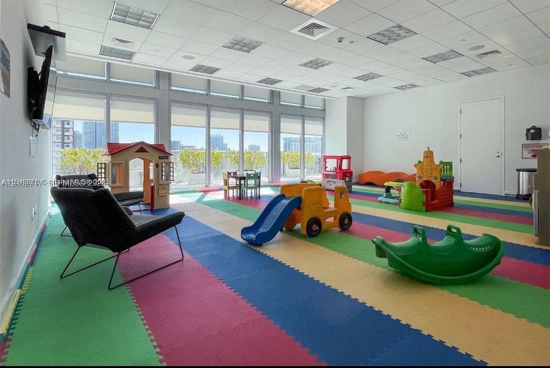 Expansive room featuring floor-to-ceiling windows, natural lighting, and multi-paneled drop ceiling tiles
